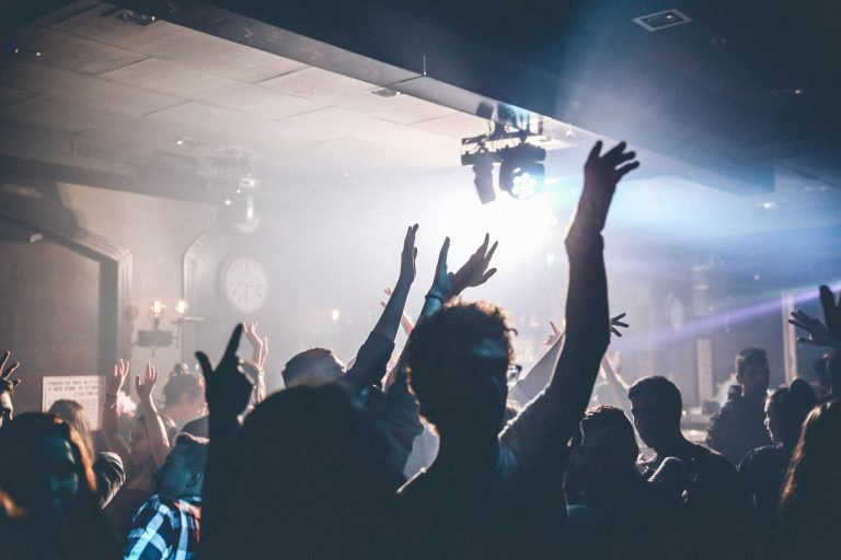 Crowd of people dancing with raised hands during a fun night out.