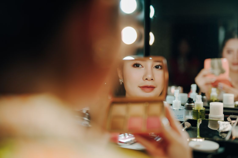 Woman looking at herself in a mirror while applying makeup and practicing self-care