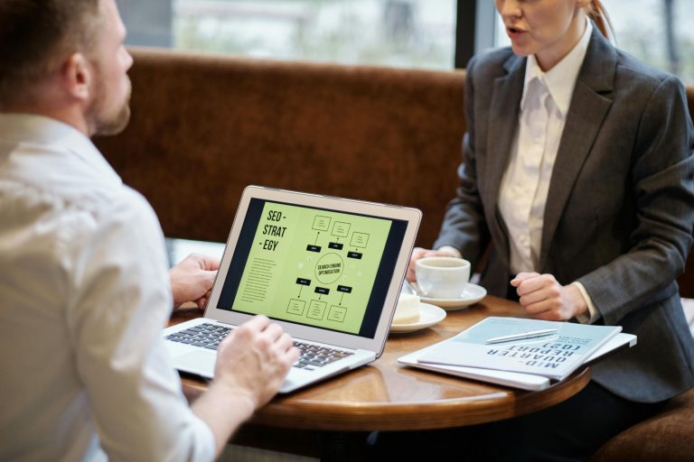 Business professionals reviewing an SEO and AEO strategy on a laptop during a consultation.