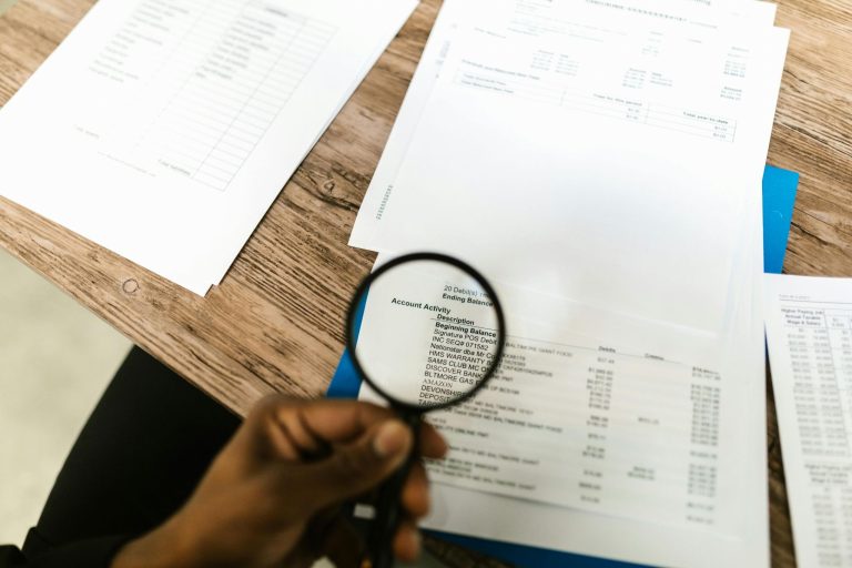 Person reviewing business documents with a magnifying glass to check important details