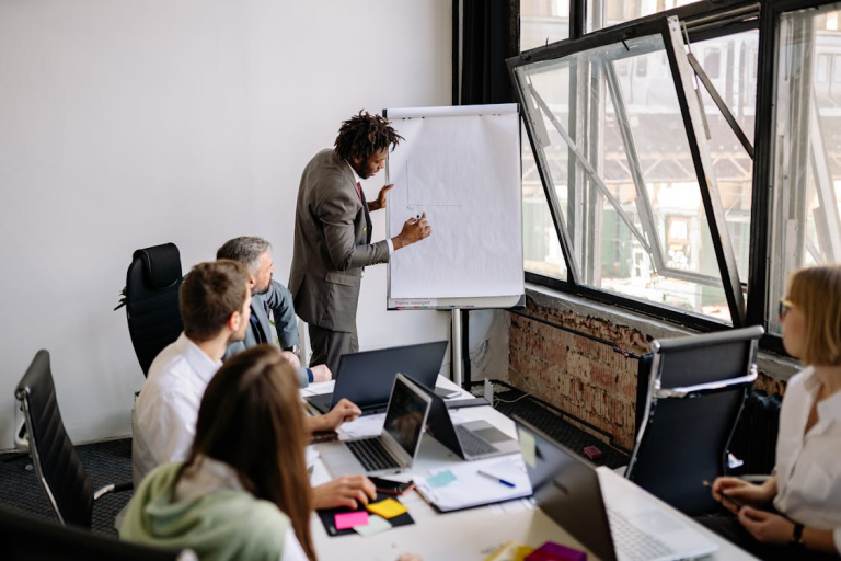 Business team in a training session while a presenter writes on a flip chart.