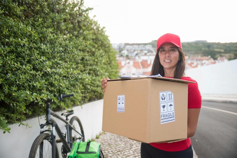 female courier holding large delivery package outdoors