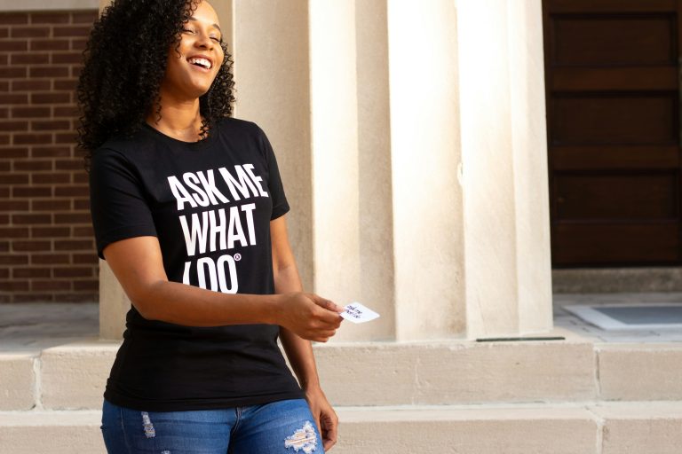 Black woman entrepreneur networking and promoting her personal brand while wearing a branded shirt.