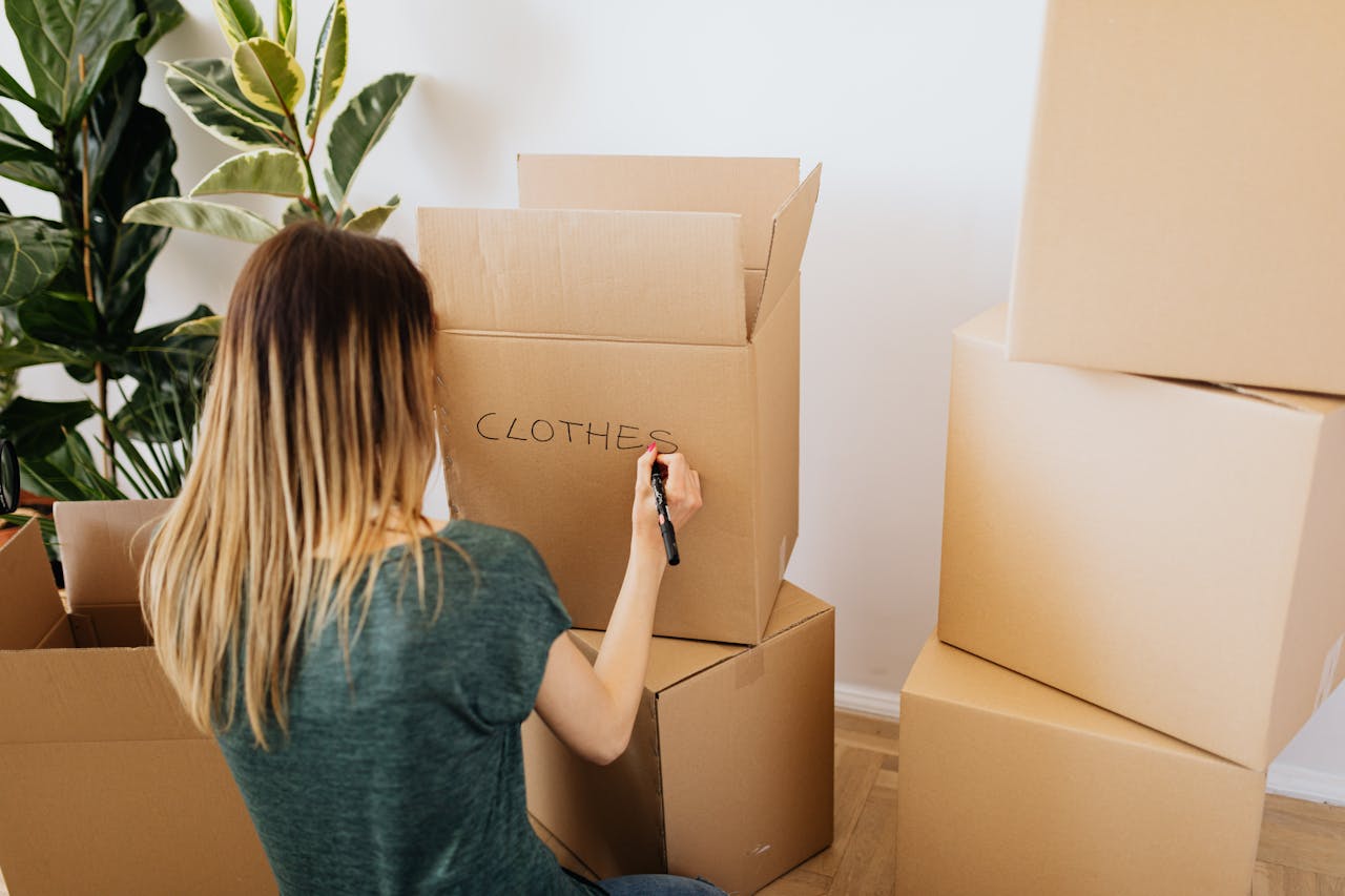 Woman labeling moving boxes while preparing for a major life transition and home move