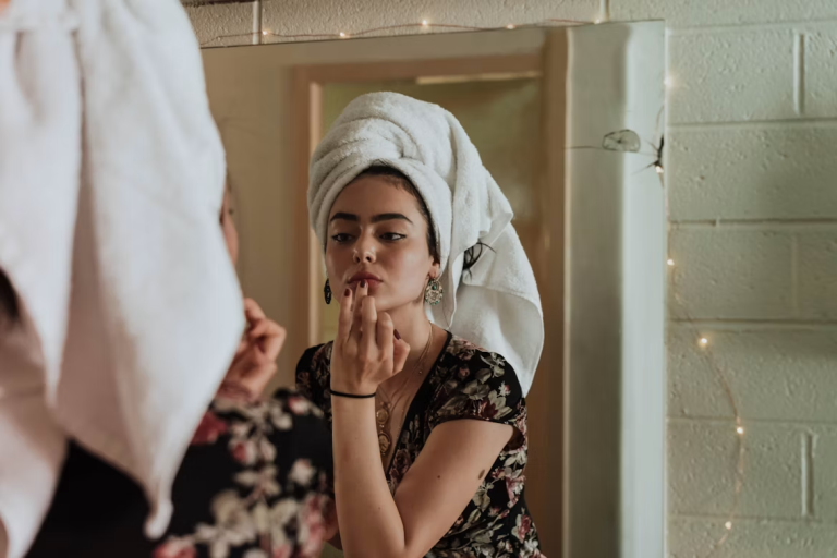 Woman applying skincare and makeup in front of a mirror during a simple beauty routine