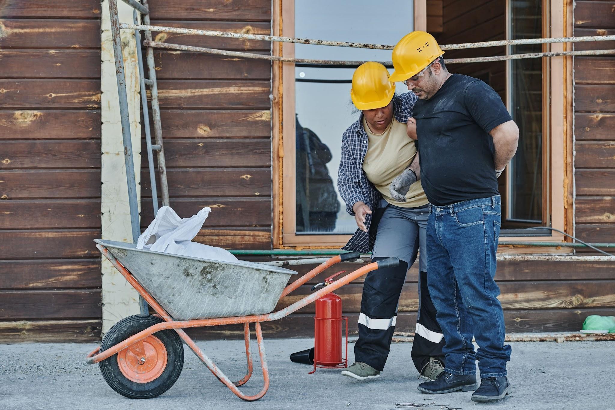 Injured construction worker being assisted by a coworker after a workplace accident