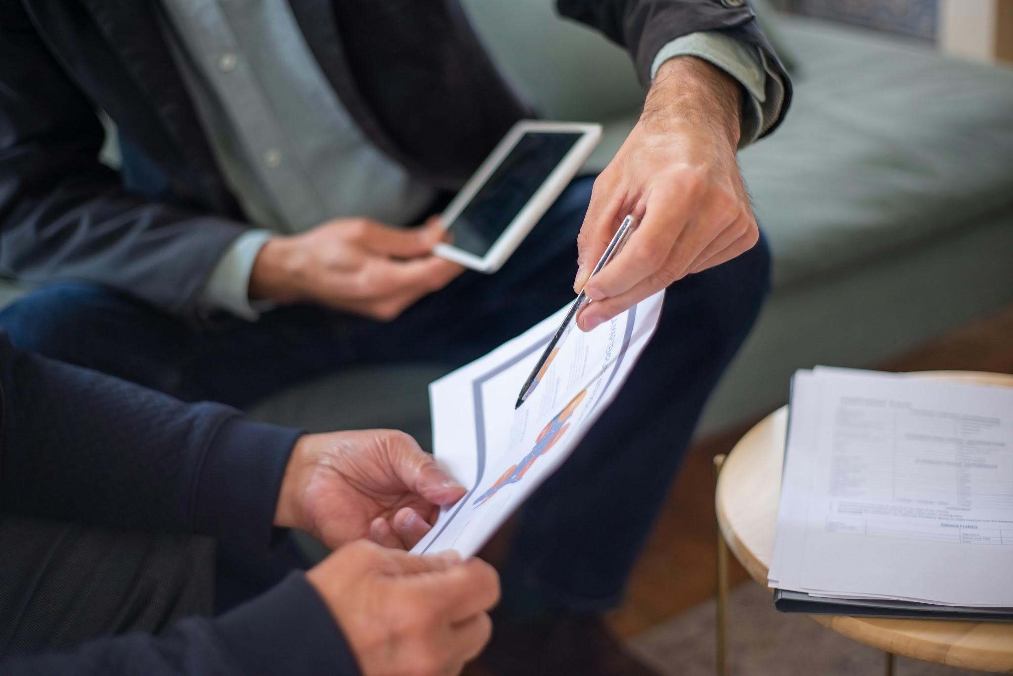 Business professionals reviewing documents and discussing a proposal during a corporate client meeting.