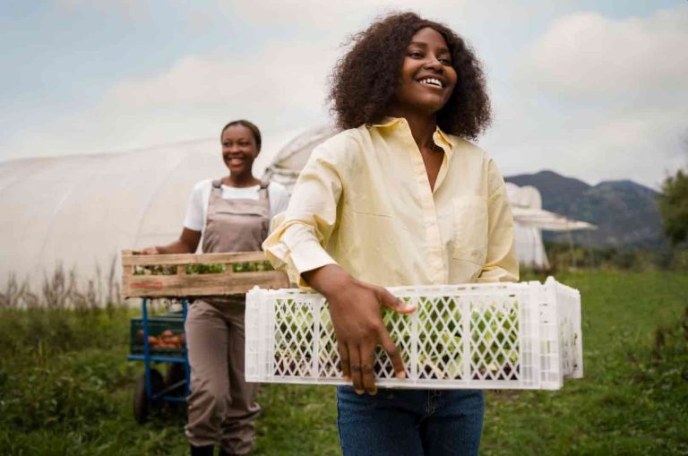 Two women farmers carrying harvested produce on a rural farm as part of a thriving agricultural business