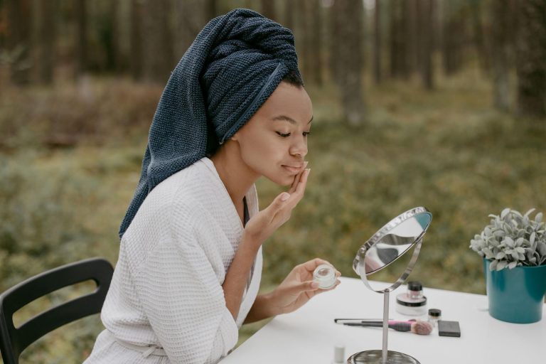 Woman applying facial cream while following a simple skincare routine focused on hydration and skin nourishment.