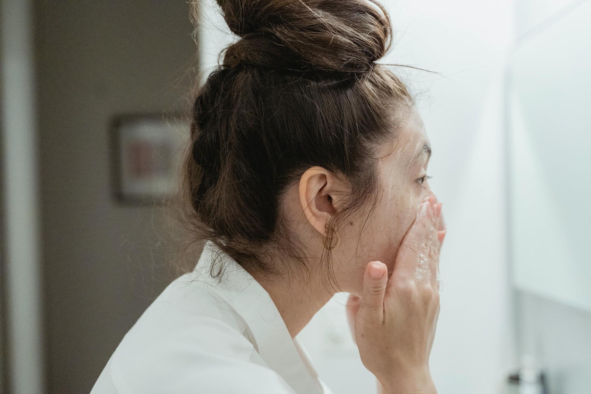 Woman gently washing her face as part of a daily skincare routine focused on healthy skin.