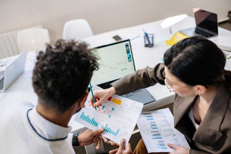 Marketing professionals reviewing campaign analytics reports and performance metrics during a business strategy meeting