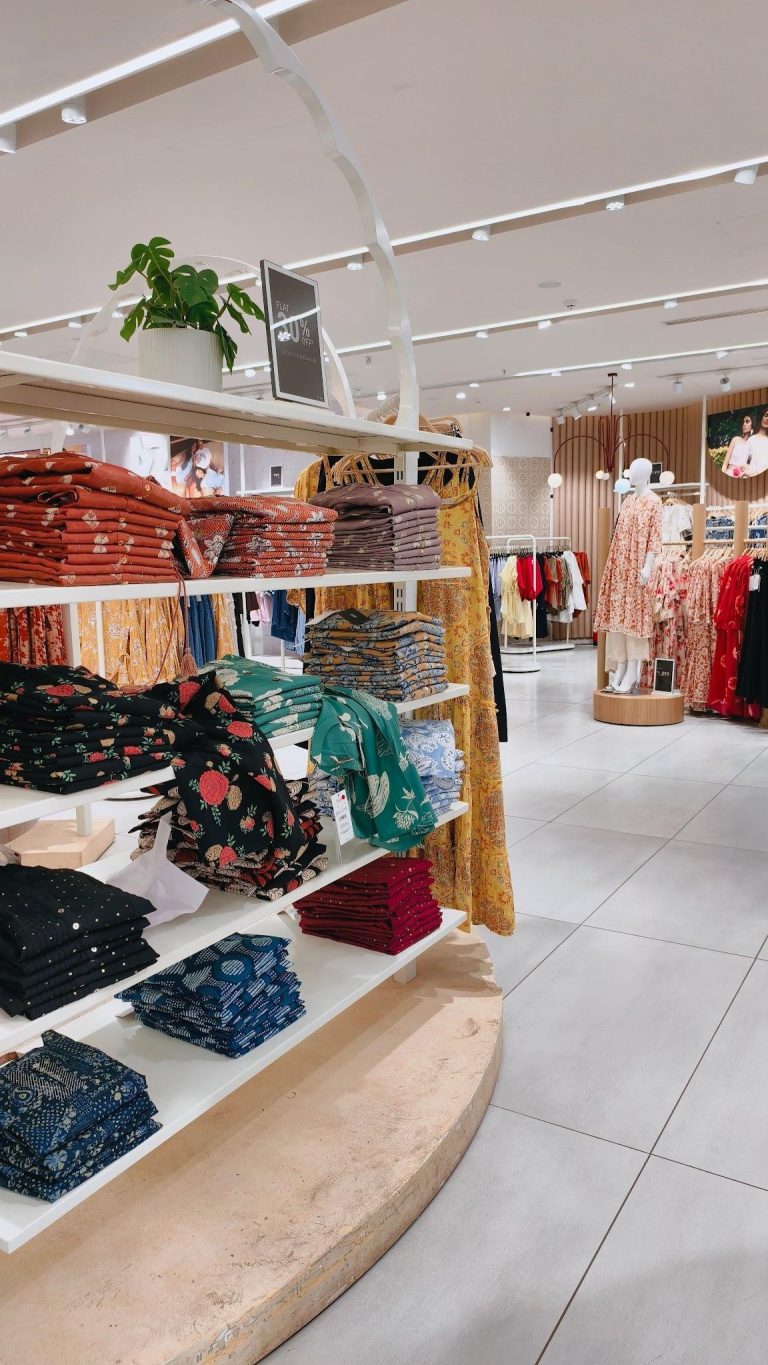 Well-organized clothing boutique with neatly displayed apparel and retail merchandise on shelves and racks.