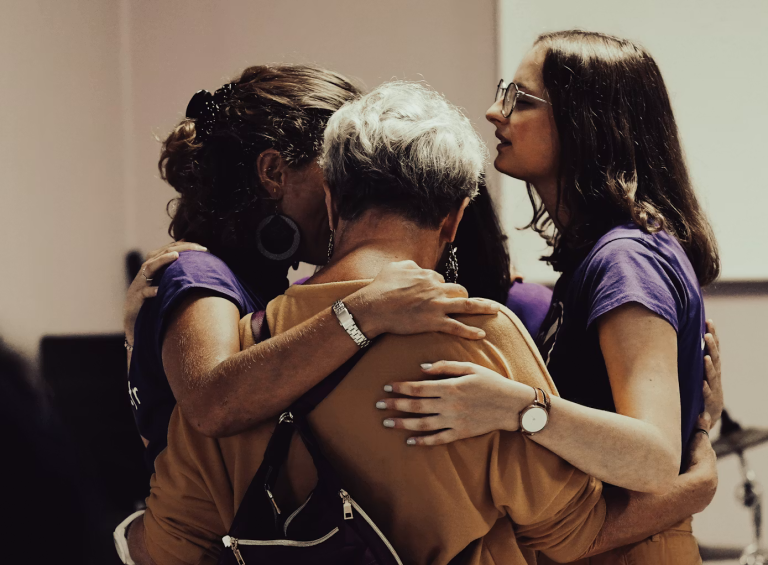 Group of women embracing each other during a support and recovery gathering