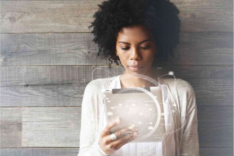 Woman using a tablet with digital marketing and online visibility graphics displayed over the screen.