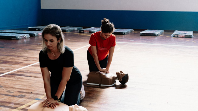 Two students practice chest compressions on CPR training manikins during a BLS CPR certification class.