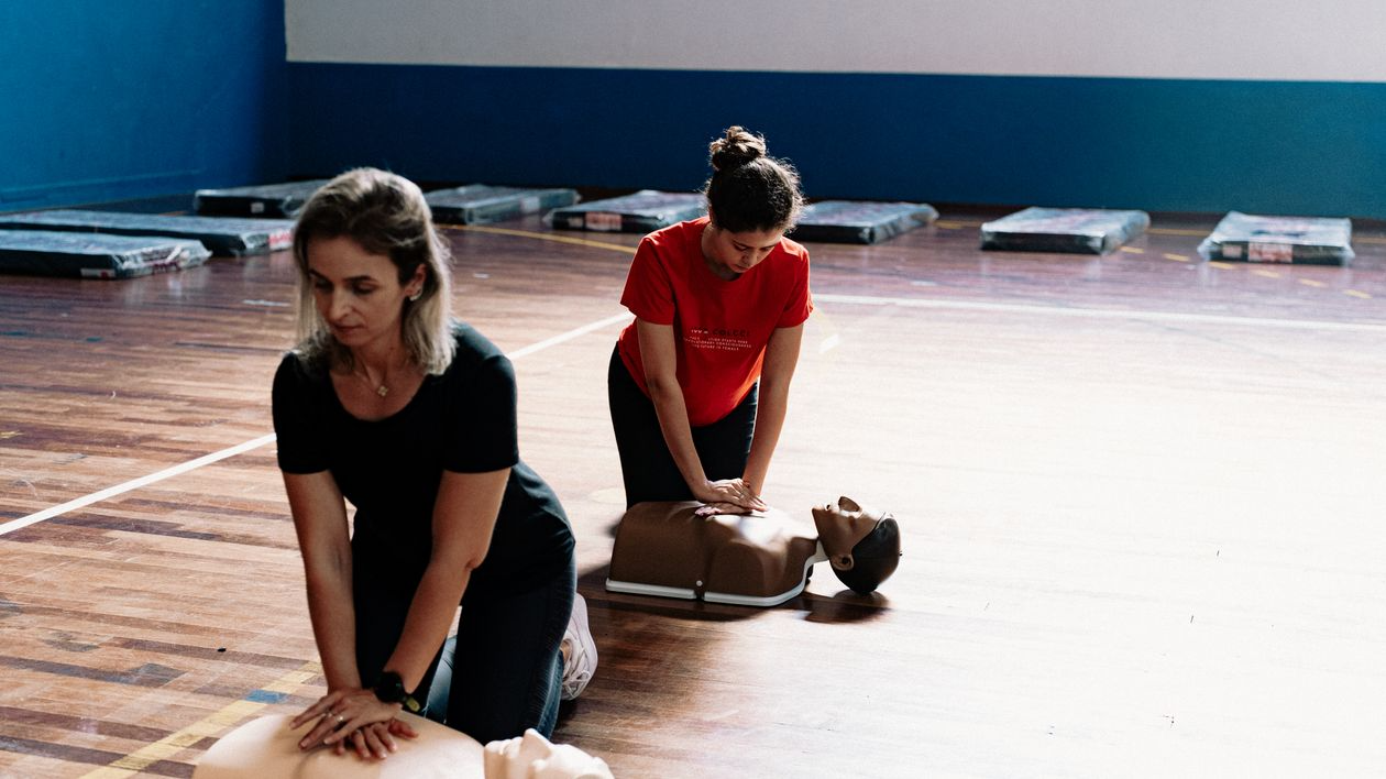 Two students practice chest compressions on CPR training manikins during a BLS CPR certification class.