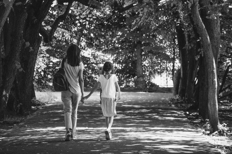 Woman and child walking together on a shaded path during a season of family change