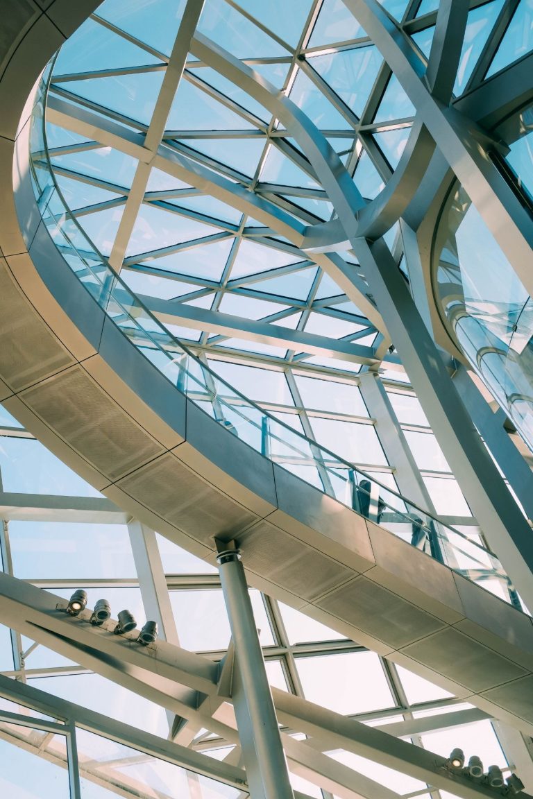 Modern commercial building interior featuring a glass ceiling, steel framework, and abundant natural light