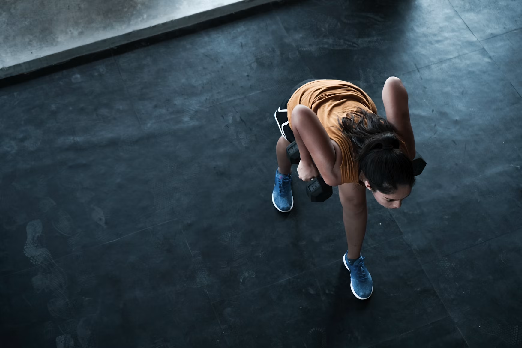 Woman performing a dumbbell exercise during a strength training workout at the gym.