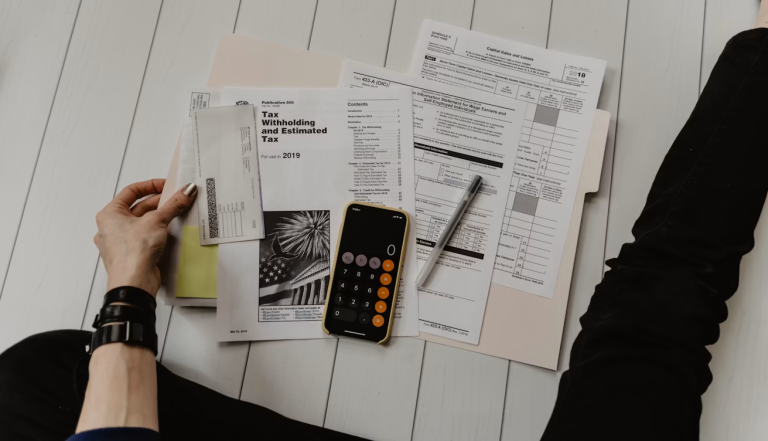 Person reviewing financial documents, calculator, and bills while creating a budget to build financial freedom.