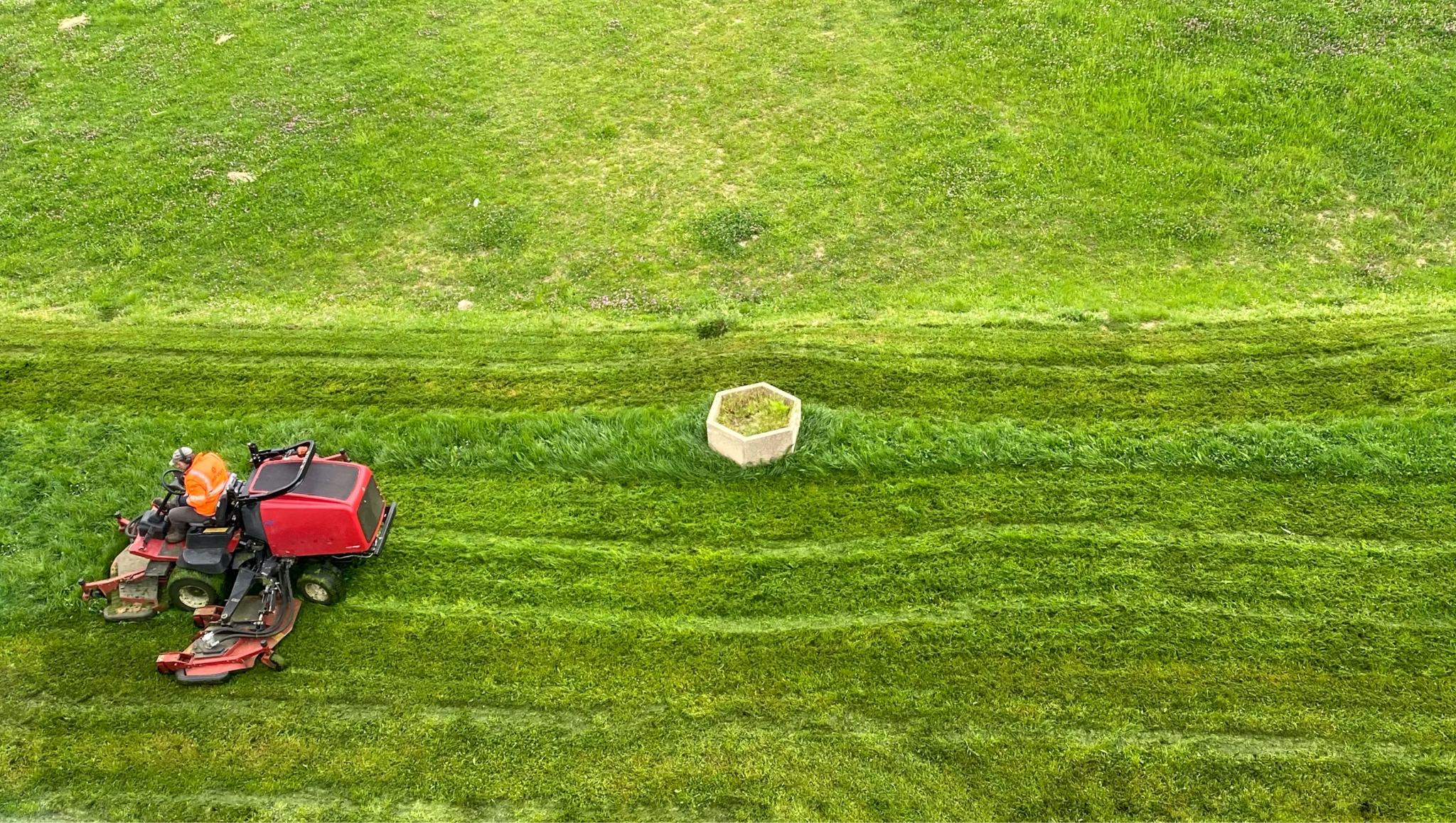 Commercial lawn mower maintaining a large grassy area to improve the appearance of a rental property landscape.