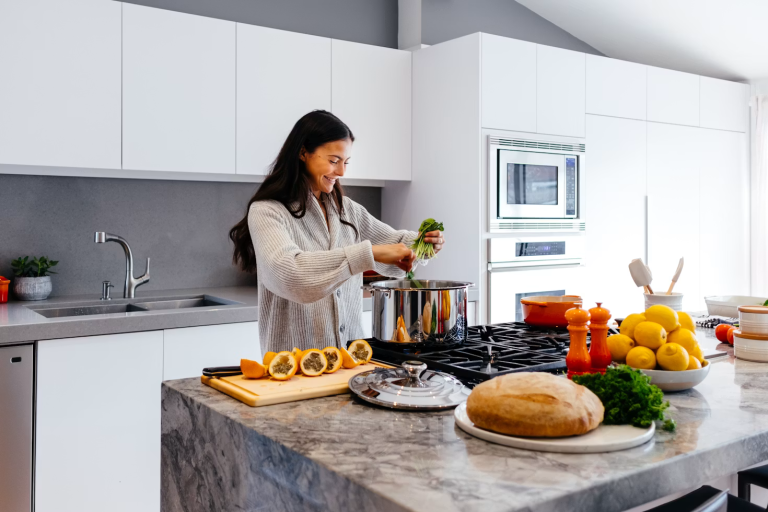 Woman preparing a healthy homemade meal with fresh vegetables and whole foods in a bright modern kitchen.