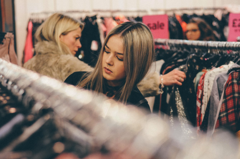 Woman browsing clothing racks while shopping for pieces that reflect her personal style and boost confidence.