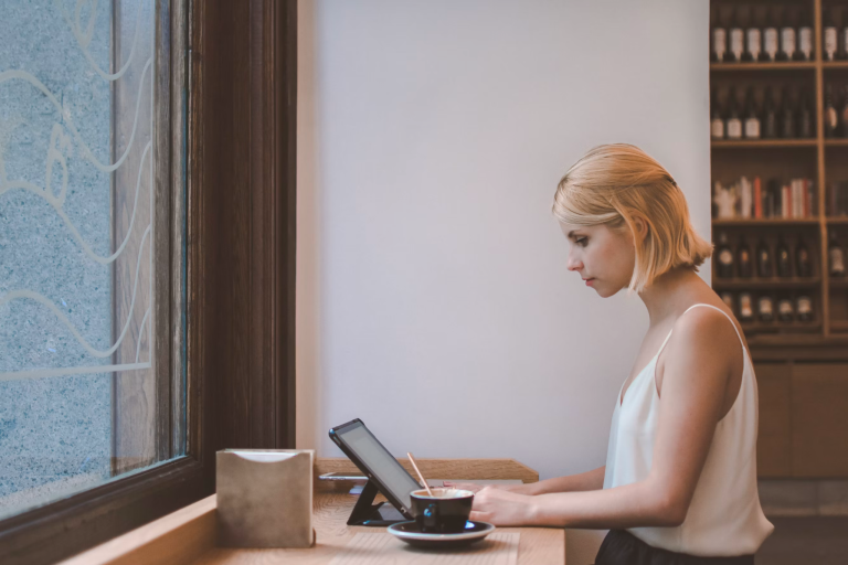 Business owner working on a tablet in a café while building a strong online presence for her business.