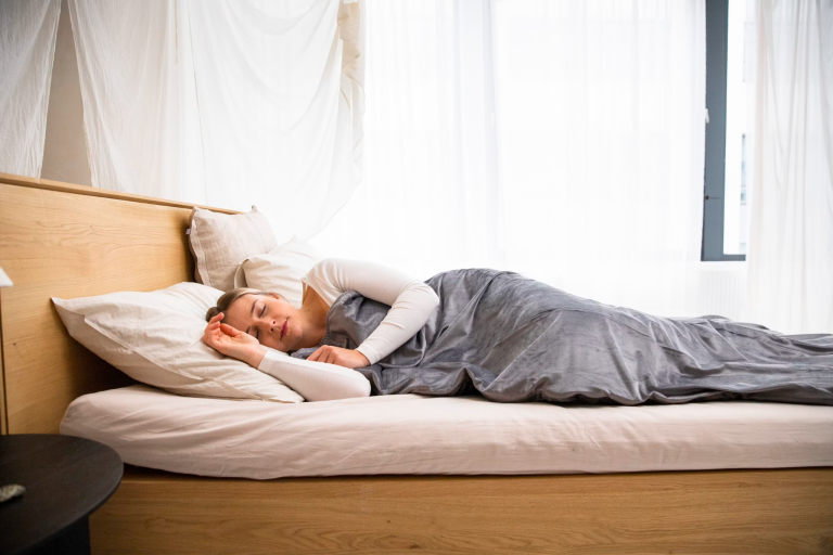 Person sleeping peacefully in a comfortable bed, highlighting the importance of quality sleep for productivity and overall wellness.