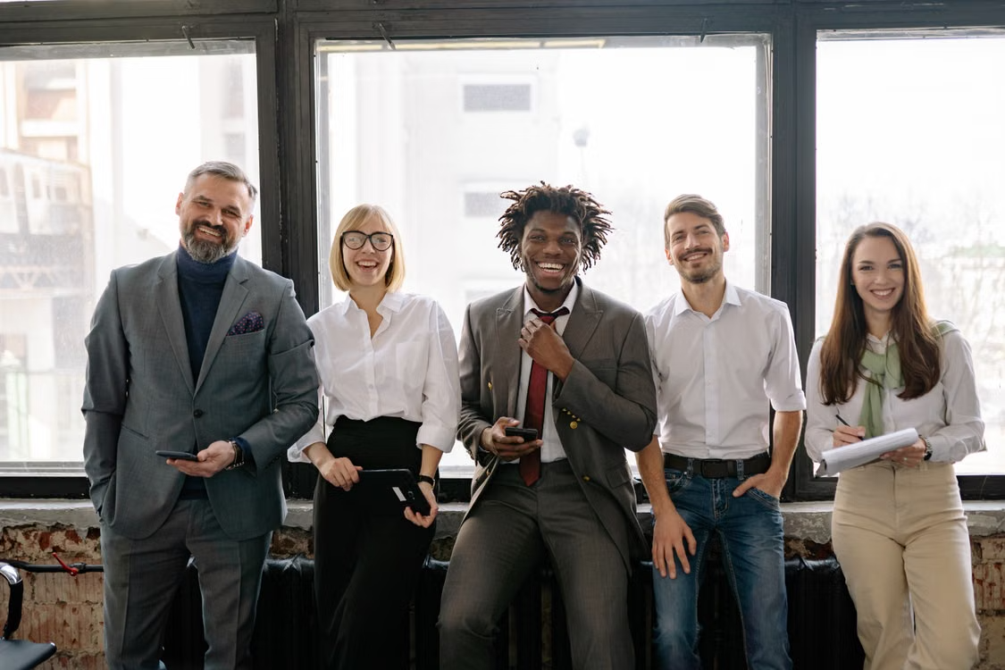 A diverse group of professionals standing together in a modern office, representing teamwork, collaboration, and successful hiring.