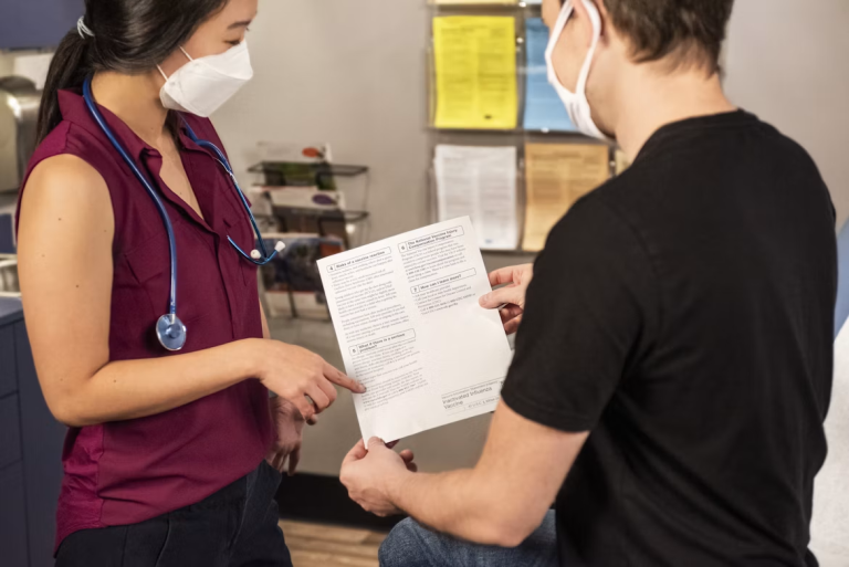 Healthcare professional reviewing paperwork with a patient during an appointment.
