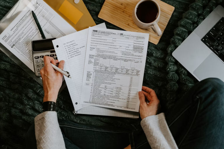 Person reviewing tax forms, calculator, and financial documents while preparing to file a tax return.
