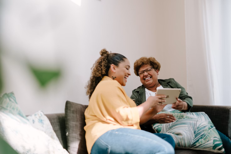 Adult daughter and her aging mother reviewing information together while discussing senior care decisions at home.