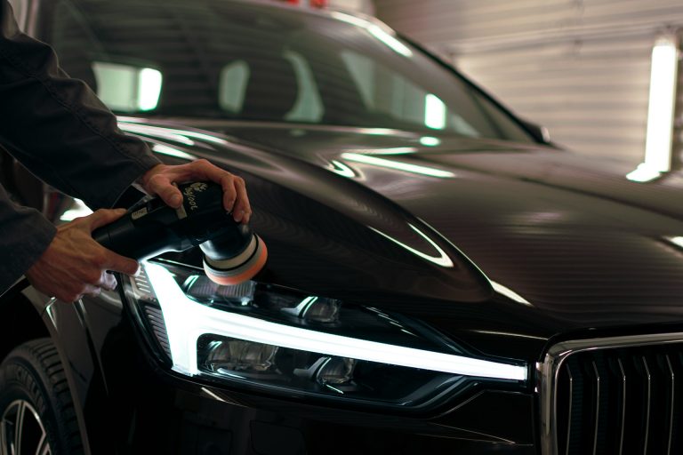 Car being polished with an electric buffer to restore and protect the paint finish