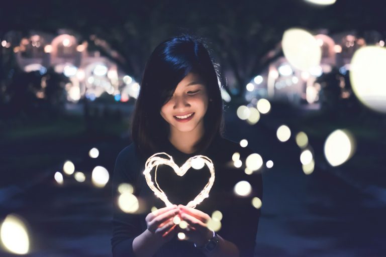Woman holding a glowing heart representing self-trust, confidence, and listening to your own voice