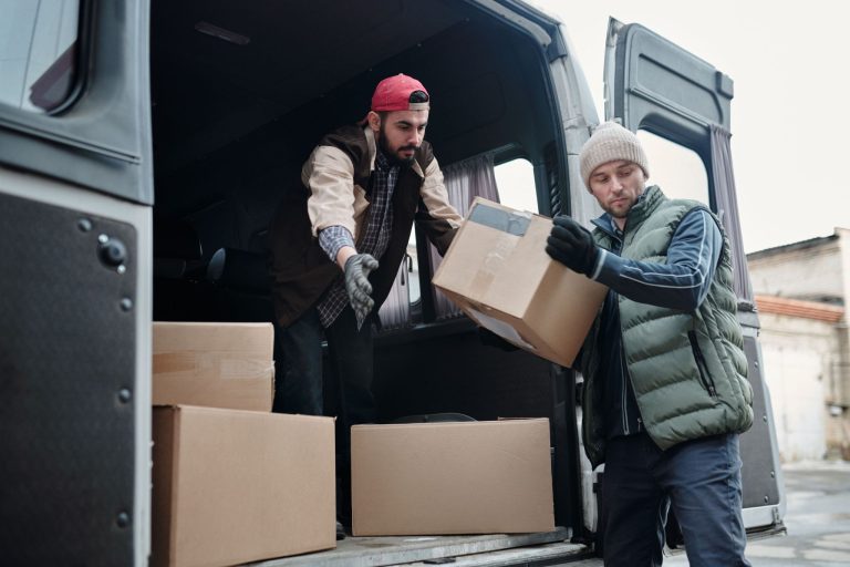 Professional movers carefully load packed moving boxes into a moving van during a residential move.