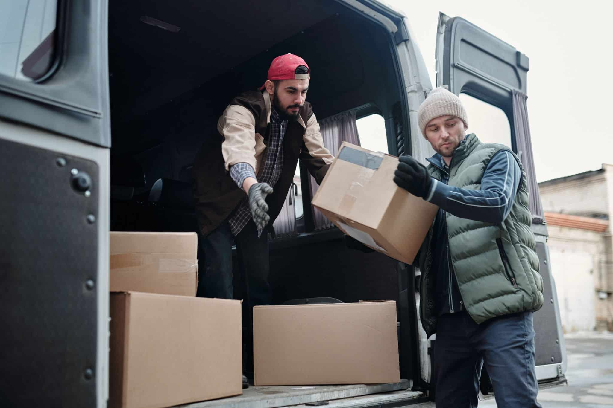 Professional movers carefully load packed moving boxes into a moving van during a residential move.