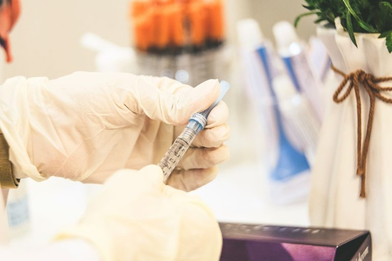 Gloved hands holding a medication syringe in a healthcare setting
