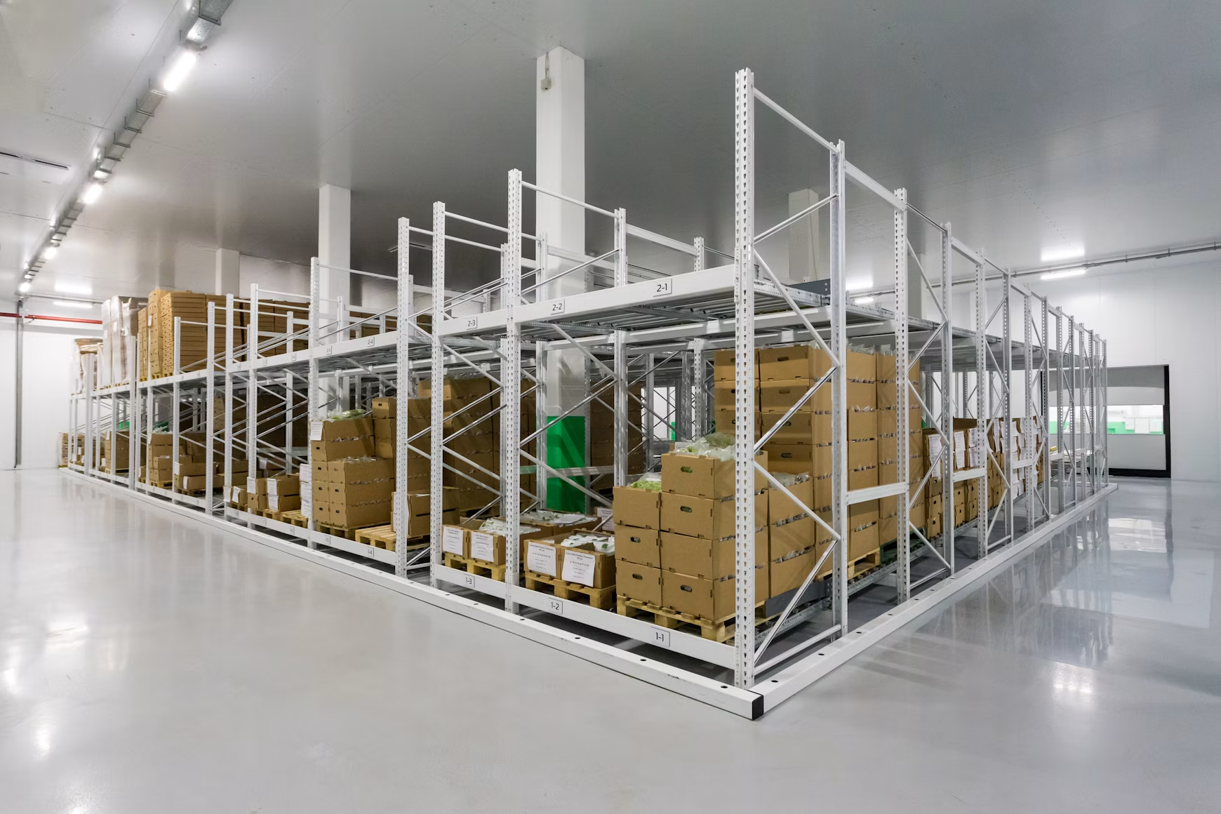 Clean warehouse with organized metal storage racks holding stacked boxes and palletized inventory.