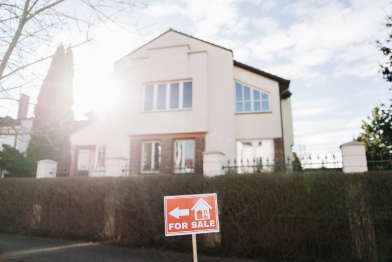 Two-story home with a red for-sale sign displayed in front of the property.