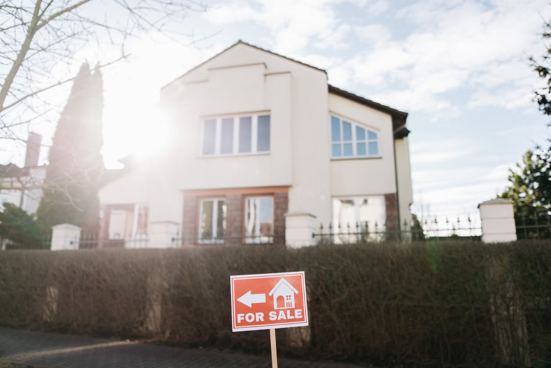 Two-story home with a red for-sale sign displayed in front of the property.