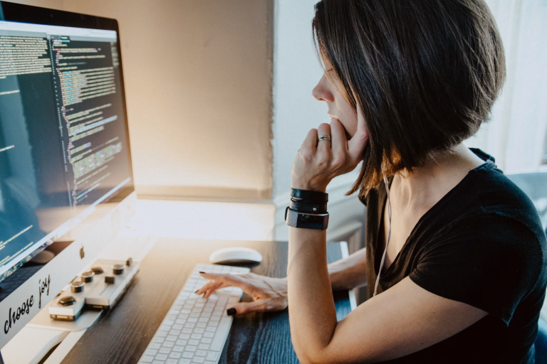 Businesswoman reviewing code and data on a desktop computer while planning a lead generation strategy.