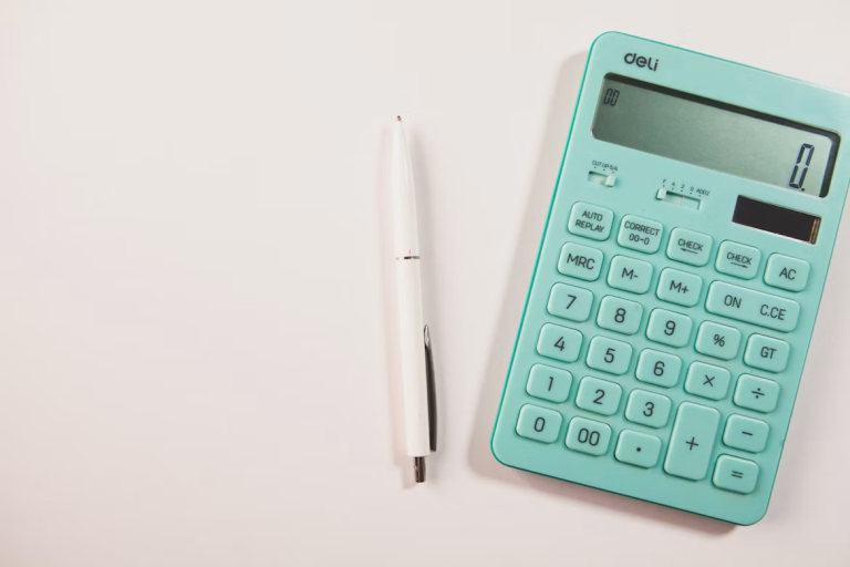 Teal calculator and white pen on a white surface for divorce financial planning.