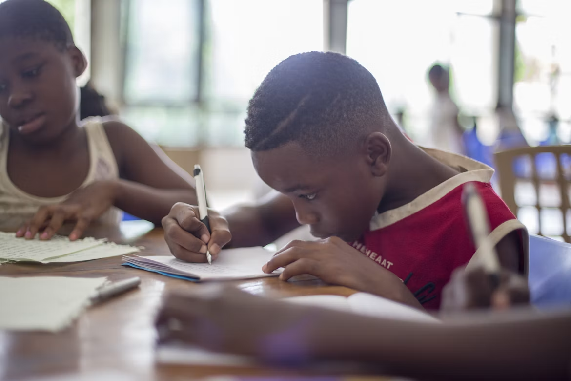 Two students writing in notebooks during a classroom activity.