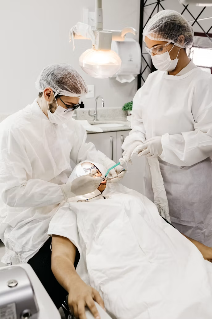 Two dental professionals provide treatment to a patient in a dental clinic.