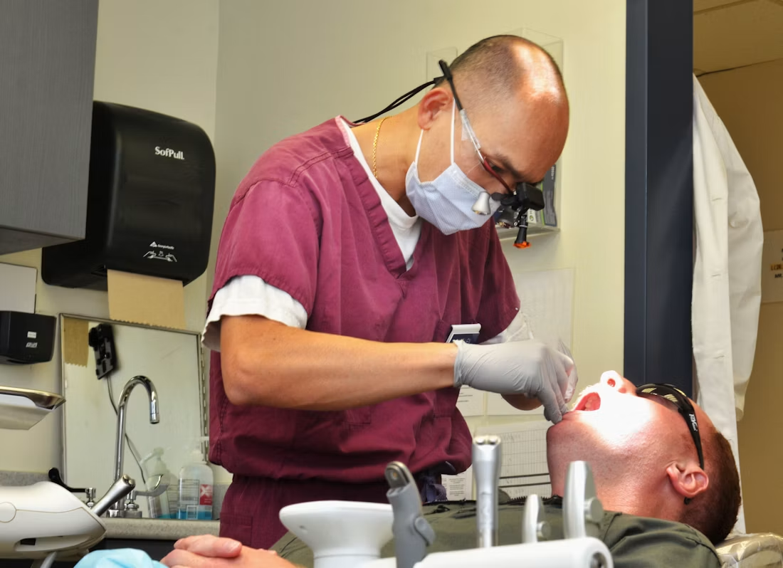 Dental professional examining a patient’s teeth in a clinical setting.