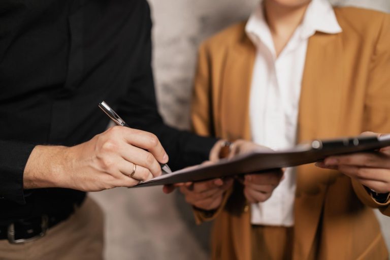 Person signing financial documents while reviewing graduate student loan information
