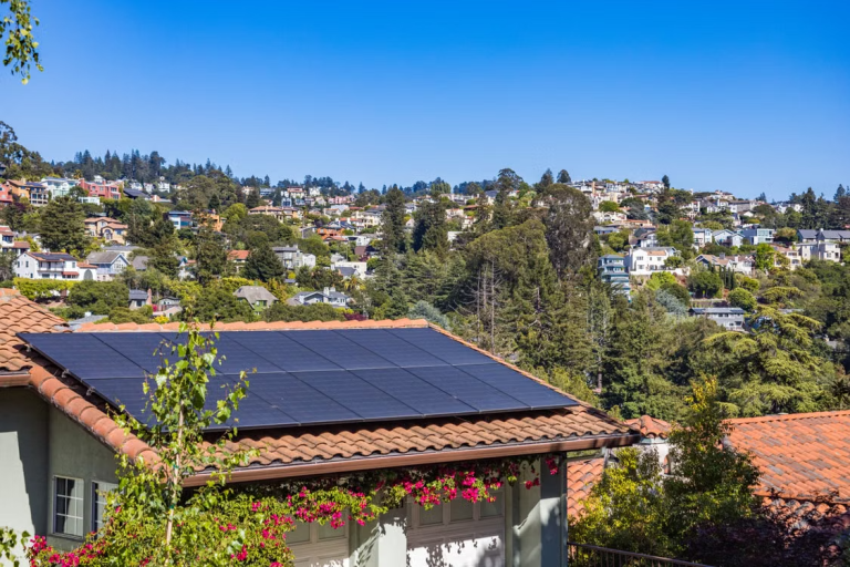 Rooftop solar panels installed on a tiled home in a leafy residential neighborhood.