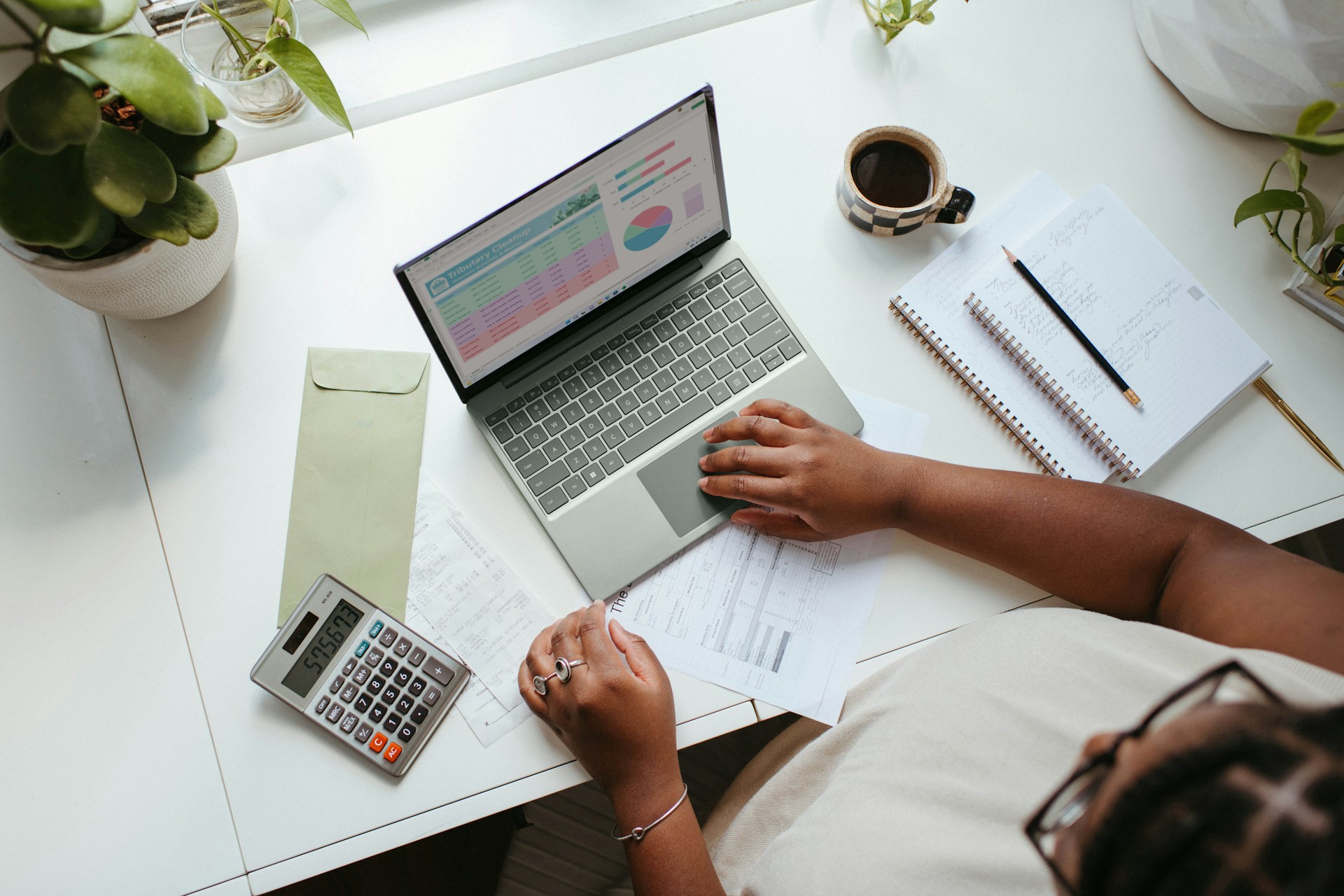 Woman reviewing financial information on a laptop with a calculator and notes