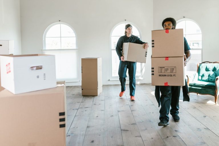 Professional movers carrying labeled cardboard boxes through a home